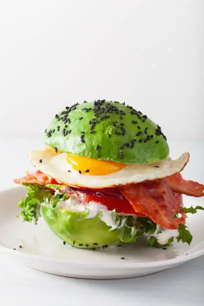 Photo of keto paleo diet avocado breakfast burger with bacon, egg, tomato