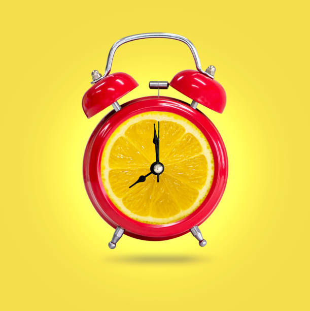 istock Alarm clock twin Bell-type red with fresh yellow lemon background. 1156437099