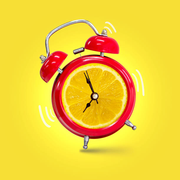 istock Alarm clock twin Bell-type red with fresh yellow lemon background. 1156437100