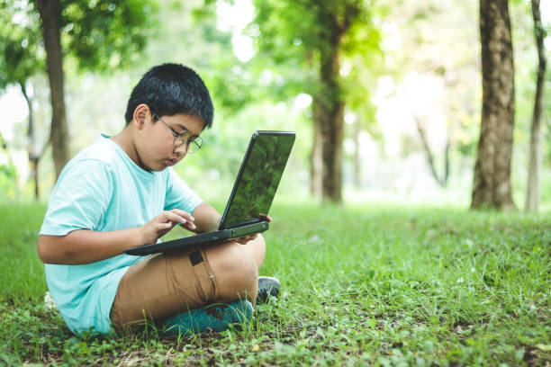 istock Boy sitting in the computer in the garden 1156437735