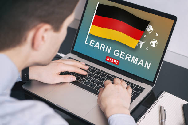 istock Man working on laptop with LEARN GERMAN on a screen. Education learning german language school concept 1156440060