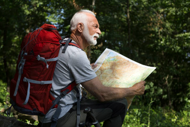 istock Senior hiker looking at map hiking in nature 1156445258