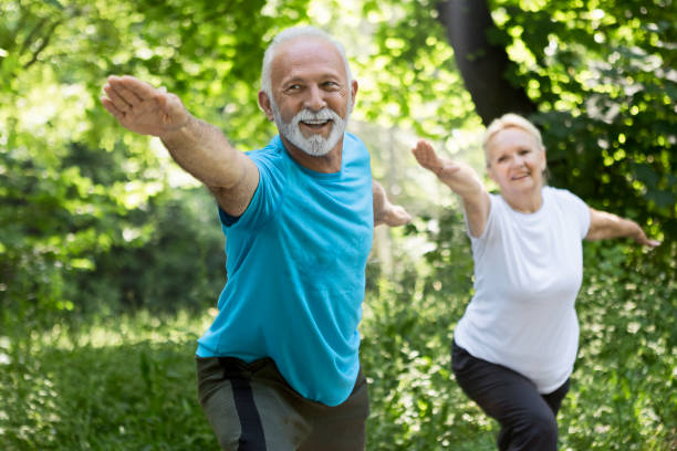 Older couple stretching ,doing yoga in park Older couple stretching in park warrior position stock pictures, royalty-free photos & images