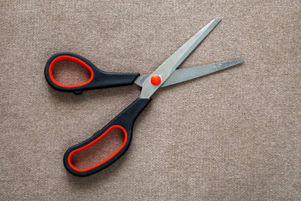 istock Close-up of sharp steel metal open scissors isolated on light cloth copy space background. Household equipment, office or school tools. 1156452523
