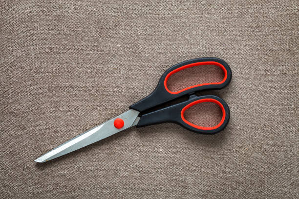 istock Close-up of sharp steel metal scissors isolated on light cloth copy space background. Household equipment, office or school tools. 1156452543