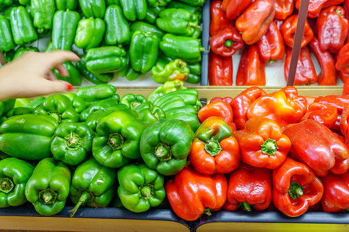 Brazilian woman buying green bell peppers