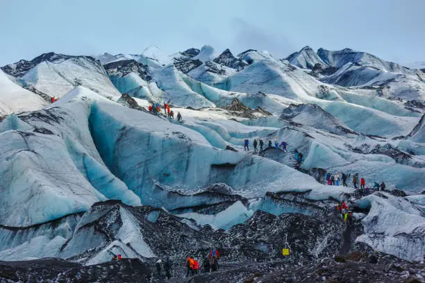 Private guide and group of hiker walking on glacier at Solheimajokull, Iceland