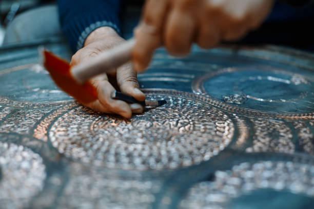 istock Craftsman doing engravings on a metal plate 1156455984