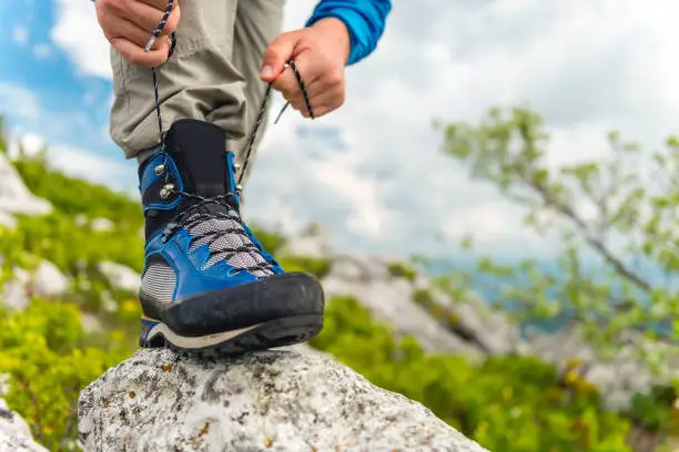 Male hiker holding his leg on a rock, and Tying Boot Laces