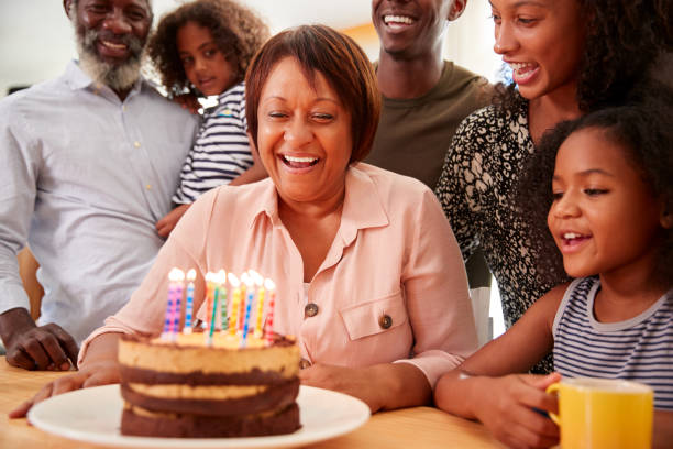 Multi-Generation Family Celebrating Grandmothers Birthday At Home With Cake And Candles Multi-Generation Family Celebrating Grandmothers Birthday At Home With Cake And Candles woman birthday cake stock pictures, royalty-free photos & images