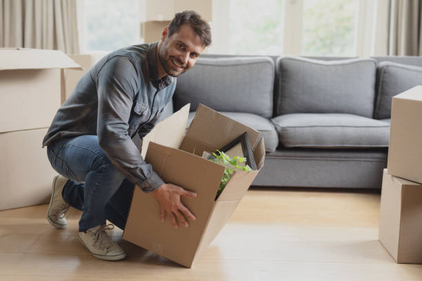 istock Man keeping down cardboard box in new home 1156460255