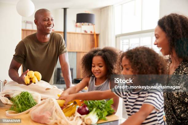 Family Returning Home From Shopping Trip Unpacking Plastic Free Grocery Bags Stock Photo - Download Image Now
