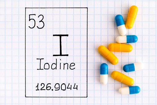 Handwriting chemical element Iodine I with some pills. Close-up.