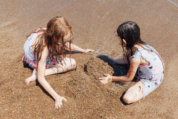 istock Playful girls make to building sandcastles 1156461831