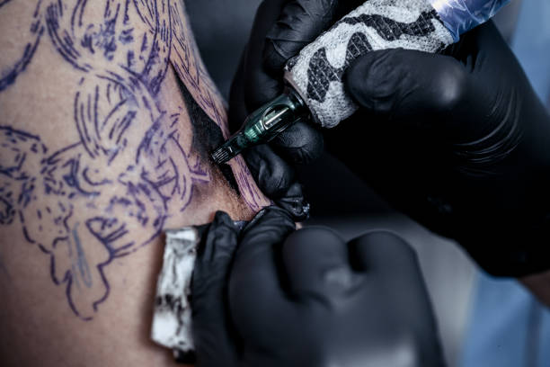istock Tattoo artist making tattoo on customer's hand 1156462718