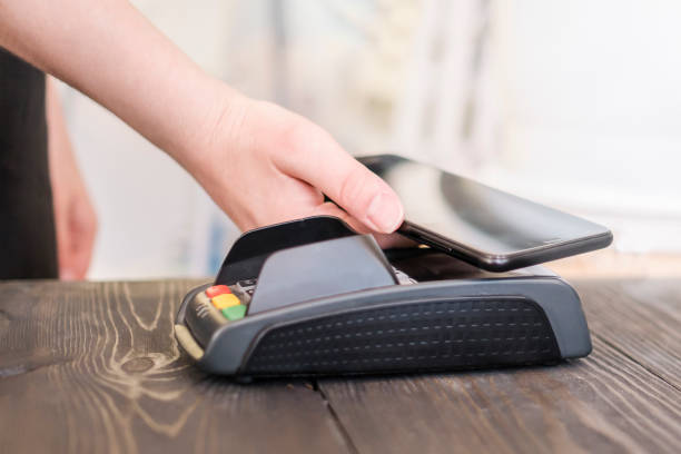 istock Woman using terminal for contactless payment with smartphone 1156462841