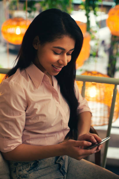 istock Young lady smiling while sending messages from her smartphone 1156465455