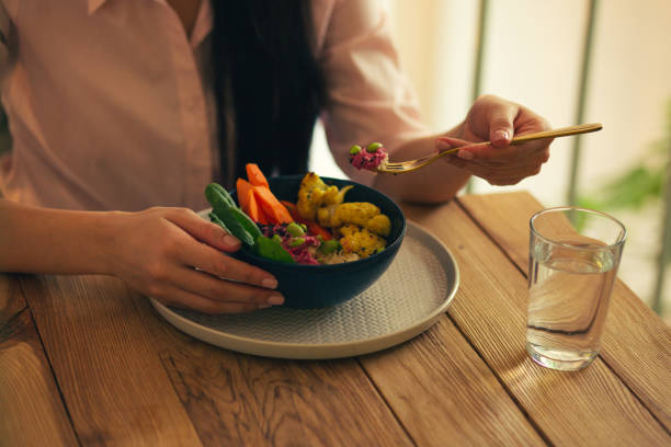 istock Bowl of vegetable meal and hand taking it with fork 1156465501