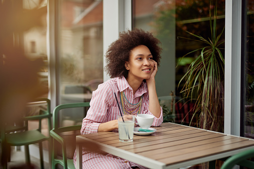 Attractive mixed race woman sitting in cafe and enjoying her coffee.