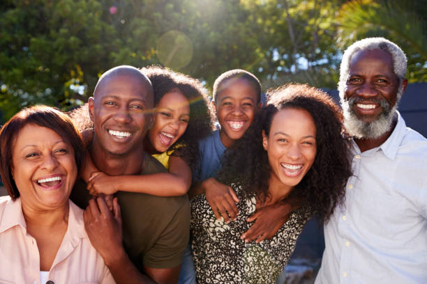 Outdoor Portrait Of Multi-Generation Family In Garden At Home Against Flaring Sun Outdoor Portrait Of Multi-Generation Family In Garden At Home Against Flaring Sun african american ethnicity stock pictures, royalty-free photos & images