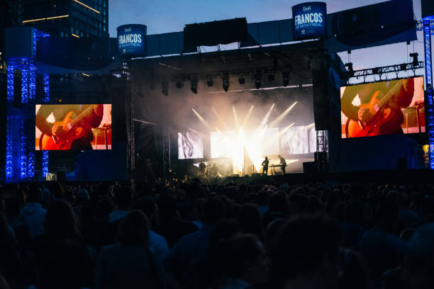 The Spectators are watching a concert at the Downtown Montréal, Quartier de Spectacles during the Francos de Montreal French-language music festival. Les Francos de Montréal is a large annual music and performance festival held in Downtown Montreal, Quebec.