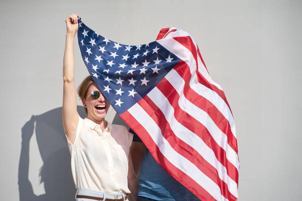 istock Young couple have fun holding USA flag, which wrapped a man 1156470621
