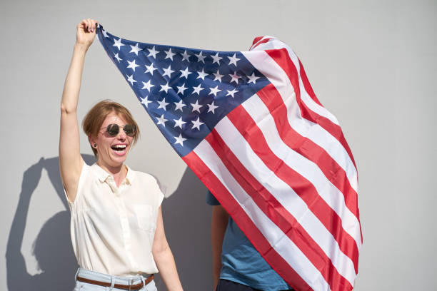 istock Young couple have fun holding USA flag, which wrapped a man 1156470645