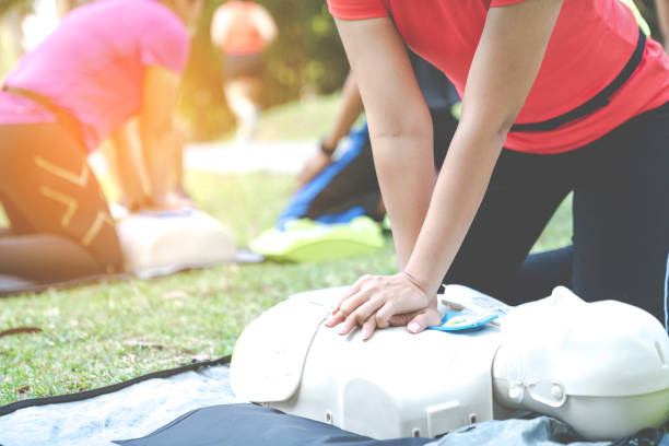 Asian female or runner woman training CPR demonstrating class in park by put hands and interlock finger over CPR doll give chest compression. First aid training for heart attack people or lifesaver. mujer asiática o mujer corredora que entrena rcp demostrando clase en el parque poniendo las manos y enclavando el dedo sobre la muñeca decpr dar compresión del pecho. entrenamiento de primeros auxilios para personas de infarto o salvavidas.