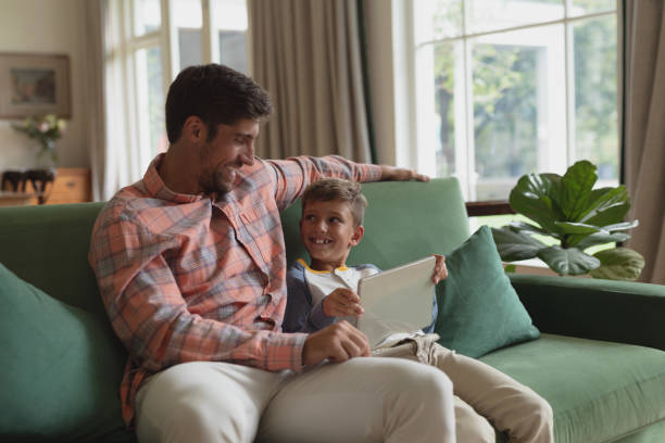 istock Father and son using laptop in living room 1156473442