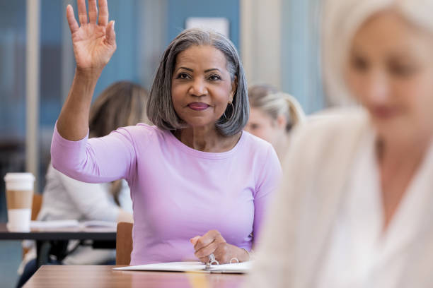 atrakcyjna dojrzała afroamerykanka podnosi rękę w klasie - adult student women mature adult library zdjęcia i obrazy z banku zdjęć