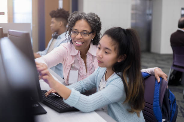 istock Librarian is pleased when young girl understands computer 1156474423