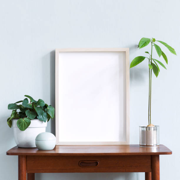 istock Stylish scandinavian interior with design retro table, white mock up photo frame and beautiful plants in design pots and accessories. Modern home decor. Gray background wall. Minimalistic concept. 1156474968