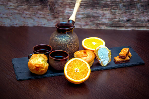 istock Ceramic cups, coffee brewing pot, orange, profiterole or eclair cakes and candies 1156475126
