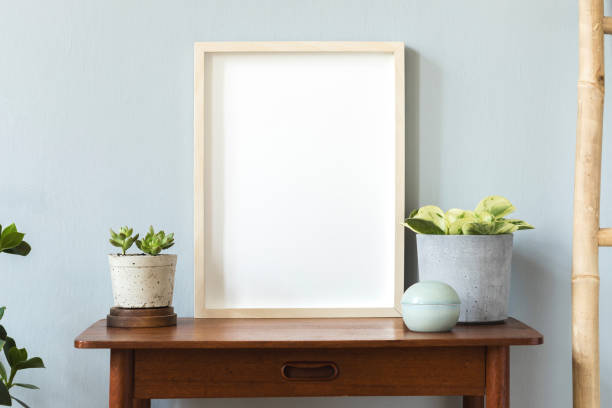 istock Stylish scandinavian room with design retro small table, mock up poster frame, elegant accessories, wooden ladder and beautiful plants in rattan pots. Minimalistic home decor. Gray background wall. 1156475136