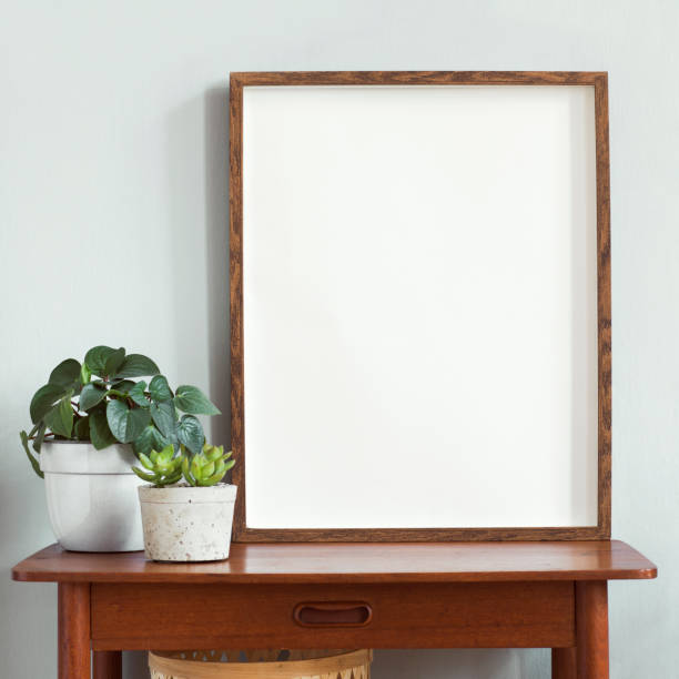 istock Stylish scandinavian interior with design retro table, brown mock up photo frame and beautiful plants in design pots. Modern home decor. Gray background wall. Minimalistic concept.Template 1156475747