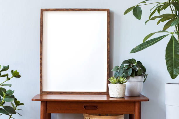 istock Stylish scandinavian interior with design retro table, brown mock up photo frame and beautiful plants in design pots. Modern home decor. Gray background wall. Minimalistic concept.Template 1156475871