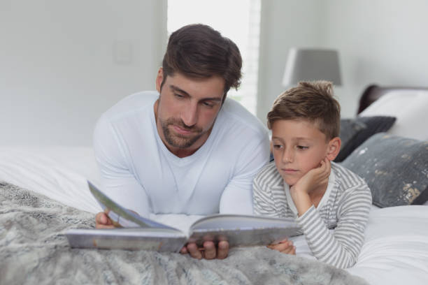 istock Father and son reading a story book in bedroom 1156476395