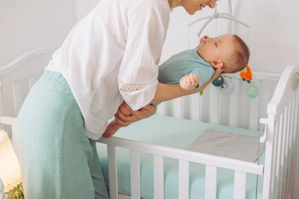 Sleeping baby Mother put gently sleeping baby in to the crib crib stock pictures, royalty-free photos & images