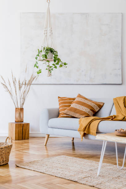 istock The modern boho compostion at living room interior with design gray sofa, wooden coffee table, rattan basket and elegant personal accessories. Honey yellow pillow and plaid. Cozy apartment. Home decor 1156477917