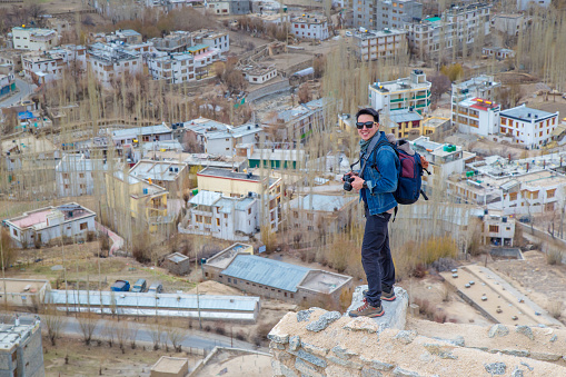 Traveler man standing on Leh Ladakh city view from Shanti Stupa. Beautiful amazing village in the valley with snow mountain at background. Ladakh, India.