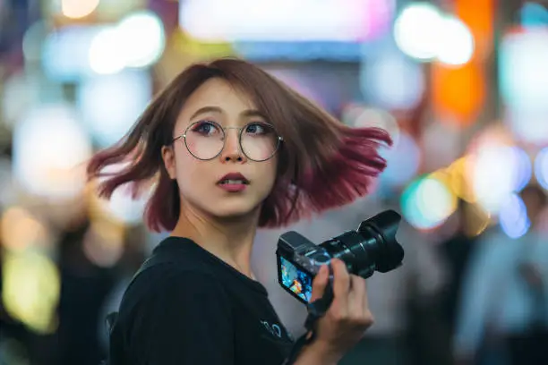 Photo of Young woman holding camera at night