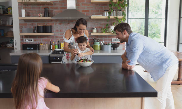 istock Family preparing vegetable salad in kitchen at home 1156480630