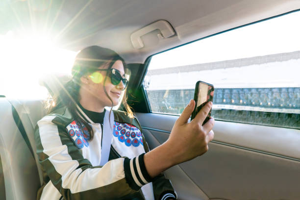 девочка-подросток, беруя селфи на заднем сиденье водородного автомоб�иля - mobile phone seat belt text messaging smiling стоковые фото и изображения