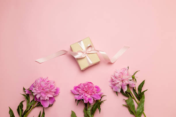 istock Creative floral composition of peonies and gift on a white and pink table background with 1156484997