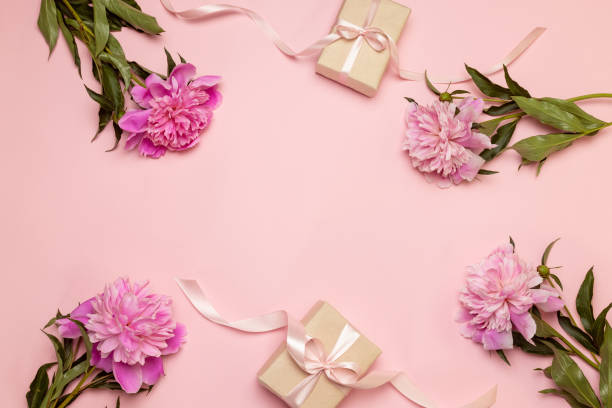 istock Creative floral composition of peonies and gift on a white and pink table background with 1156485007