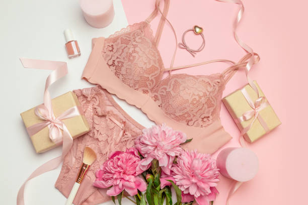 female elegant pink lace bra and panties, pink candles, hair tie, a bouquet of beautiful peonies, nail polish, jewelry, top view - panties lingerie sensuality bra imagens e fotografias de stock