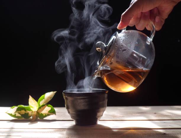 istock Pouring hot tea into a cup on black background, close up 1156491696