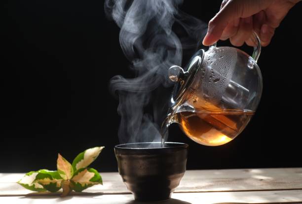 istock Pouring hot tea into a cup on black background, close up 1156491812
