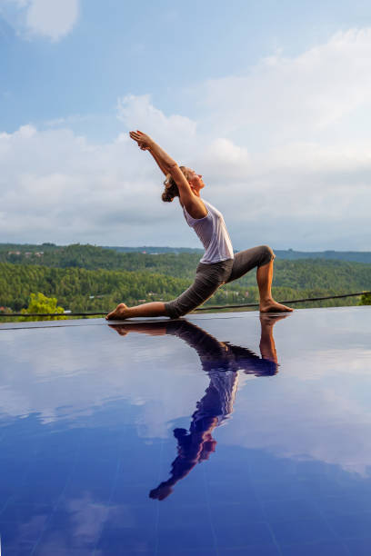 istock Caucasian woman practicing yoga by the pool 1156492335