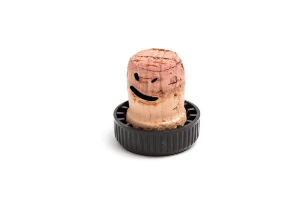Cork for wine with a black plastic hat on which is drawn a drunken smile and eyes. Isolated on white background
